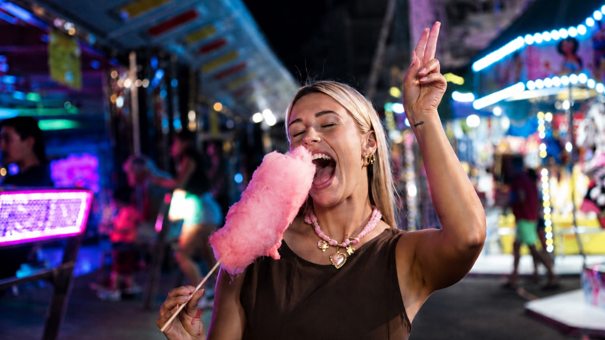 Donna con collana Le Amikette e zucchero filato tra le luci del luna park